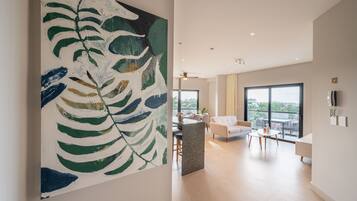 Een ruime woonkamer met een groot abstract schilderij, een moderne keuken en een balkon met uitzicht over de stad.