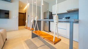 A modern kitchen with a central island, a dining area with a wooden bench, and a living room with a sofa.