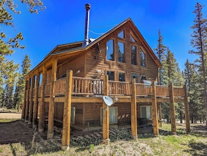 Une cabane en bois dotée d’un balcon, de grandes fenêtres et d’une cheminée.