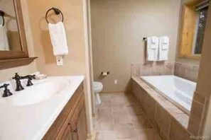 Un bany amb un lavabo doble, una banyera i un vàter.