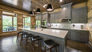 Cozinha ampla com uma ilha grande, banquetas e eletrodomésticos modernos.