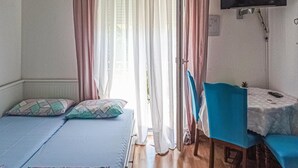A bedroom with two beds, a table, and a TV.