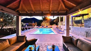 An outdoor pool area with lounge chairs and a covered seating area.
