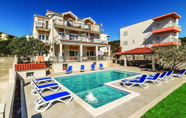 A hotel with a swimming pool, multiple balconies, and a covered outdoor seating area. - 1 bedroom awesome apartment in Poljica (Poljica)