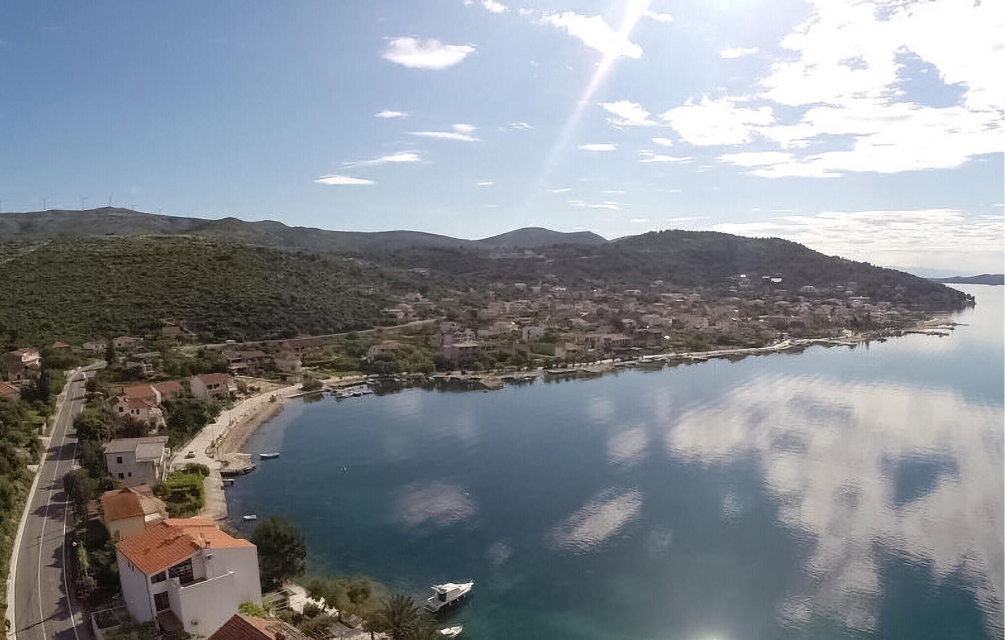 Uma cidade costeira com uma baía calma, rodeada por colinas.
