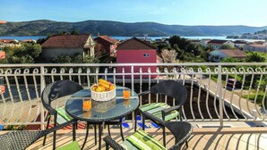 A balcony with a table and chairs, a wicker basket with fruit, and a glass of orange juice.