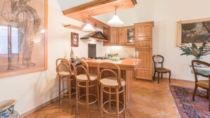 A kitchen with wooden cabinets, a central island with bar stools, pendant lighting, and a painting on the wall. - Beautiful apartment for 4 people with WIFI, TV and panoramic view (Florence)
