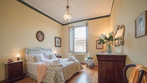 A bedroom with a bed, bedside tables, a dresser, a chair, a window, and a chandelier. - Beautiful apartment for 4 people with WIFI, TV and panoramic view (Florence)