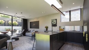 A modern kitchen with a central island, a dining area with a sofa and chairs, and a large window providing natural light.