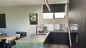 A modern kitchen with a central island, dark wood cabinetry, and a large window providing natural light.