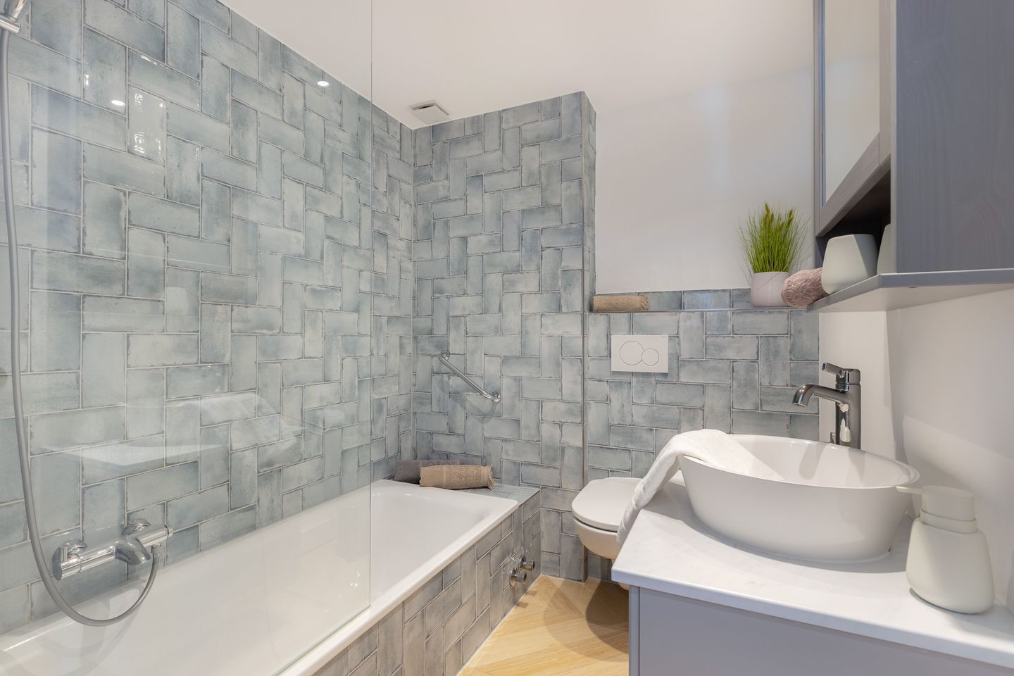 A modern bathroom with a glass-enclosed shower, a white bathtub, and a sink with a white countertop.