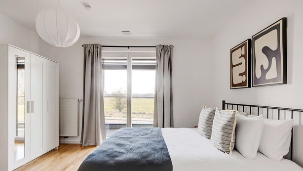 A bedroom with a large bed, a view of the outdoors, and a white wardrobe.