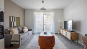 A modern living room with a sofa, a coffee table, a TV, and a dining area.
