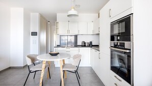 A modern kitchen with white cabinets, a round table, and two chairs.