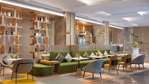Et moderne loungeområde med siddepladser, borde og en reol.