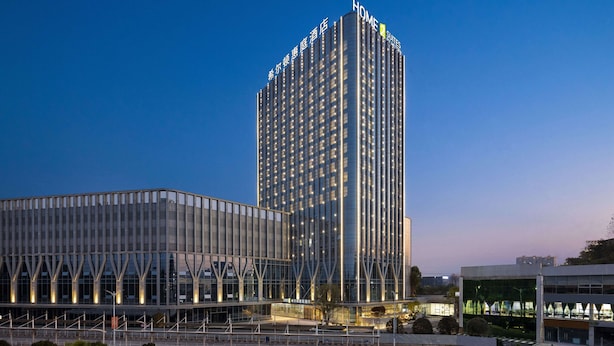 Et højt hotel med moderne design, hvor der er et markant skilt med ordet "HOME" øverst.