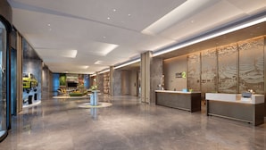 En moderne hotellobby med reception, siddeområde og en udstilling af en legetøjsbil.