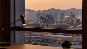 Udsigt gennem et vindue af en futuristisk by med bygninger og en statue.