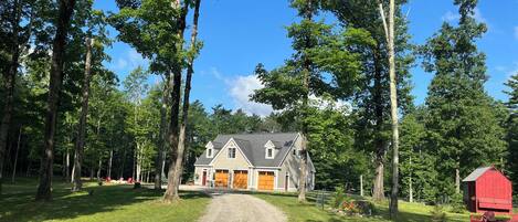 A two-story house with a gravel driveway leading to a wooden door.