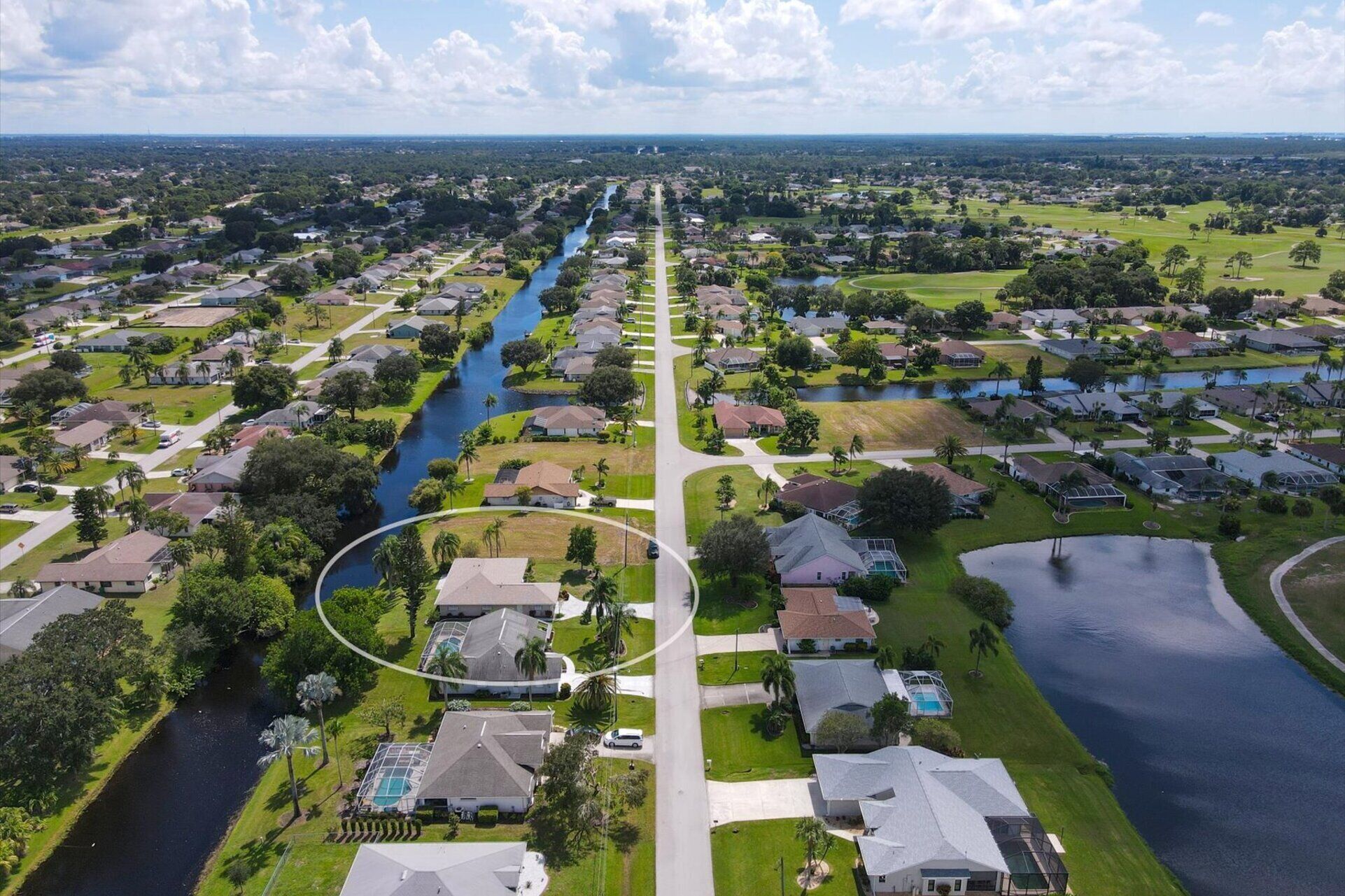 Vue aérienne d’un quartier résidentiel avec des maisons, une rivière et un terrain de golf.