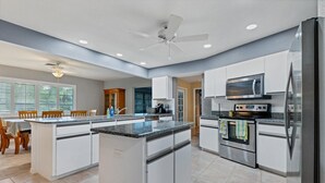 Eine moderne Küche mit weißen Schränken, einer Arbeitsplatte aus Granit, einem Edelstahlkühlschrank und einem eingebauten Backofen.