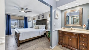 A bedroom with a bed, a nightstand, a dresser, a ceiling fan, and a large mirror. - Luxury Contemporary Style House on Charlotte Harbor Area, Charlotte County House 5819 (Charlotte County)