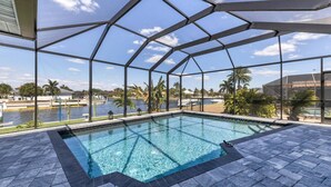 A pool with a clear view of the surrounding area, including a body of water and palm trees. - Luxury Contemporary Style House on Charlotte Harbor Area, Charlotte County House 5819 (Charlotte County)