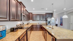 A modern kitchen with dark wood cabinets, granite countertops, stainless steel appliances, and a central island.