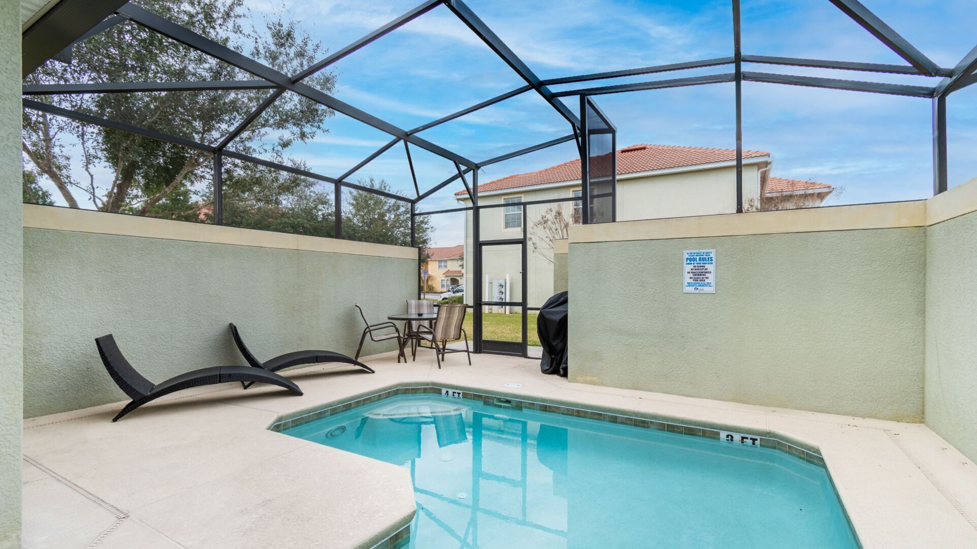 Un espace piscine extérieur abrité, doté d’une structure en verre, d’une table de billard et d’un barbecue.