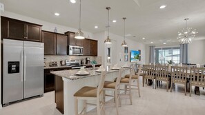 Enjoy cooking in this well-equipped kitchen with a central island, stainless steel appliances, and pendant lighting.