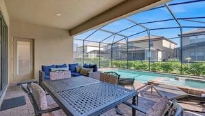 Uma área externa coberta com piscina, assentos e vista para as casas vizinhas.