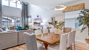 Uma sala de estar moderna com área de jantar, janelas amplas e vista para o exterior.
