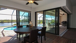 Un coin repas avec une table et des chaises, un vase, et une vue sur une piscine et un lac.
