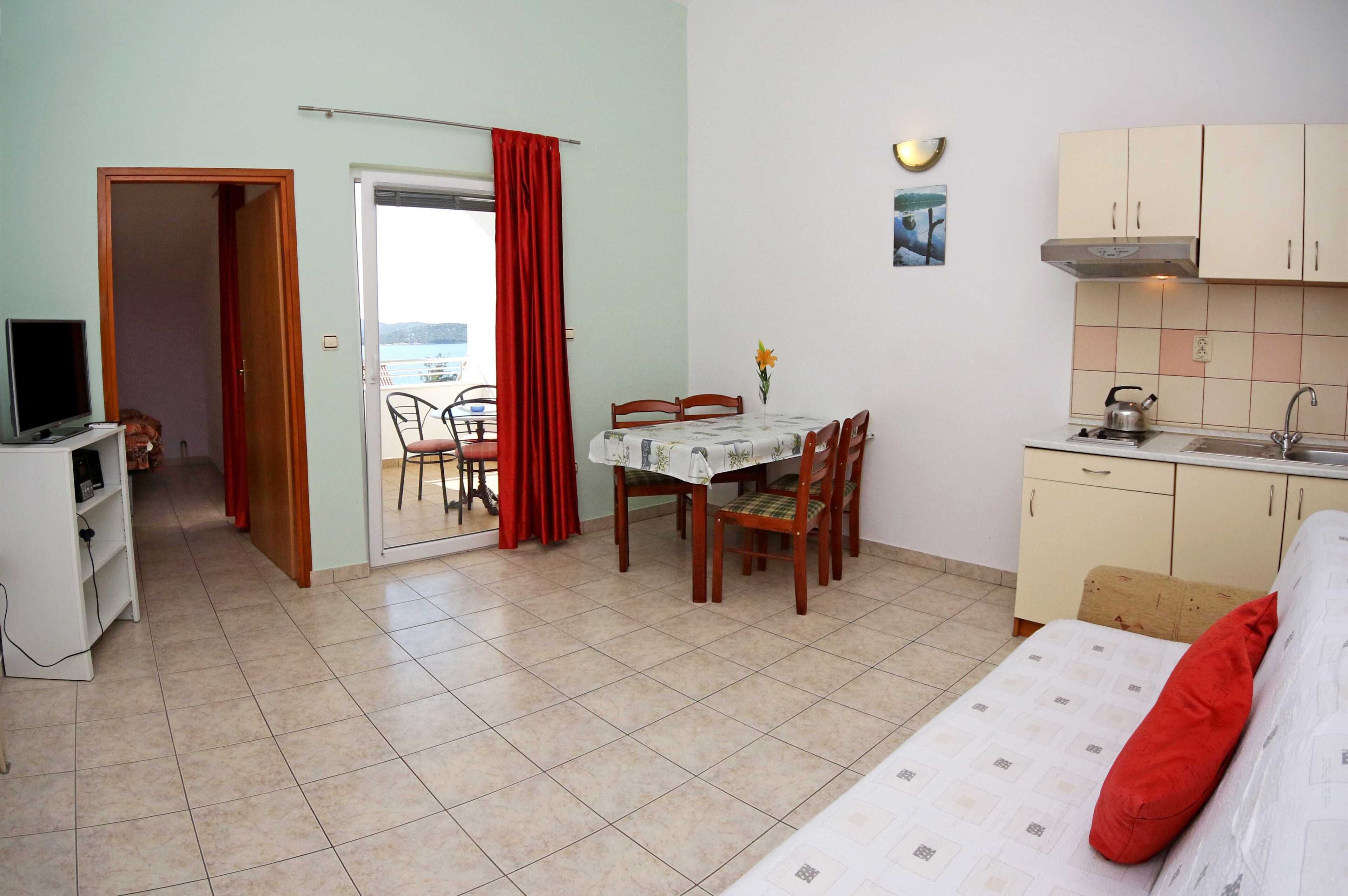 A compact living space with a dining area, kitchenette, and a bed.
