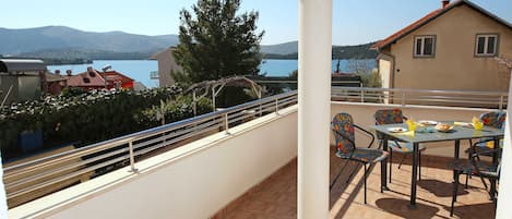 A balcony with a table and chairs, overlooking a lake and mountains.
