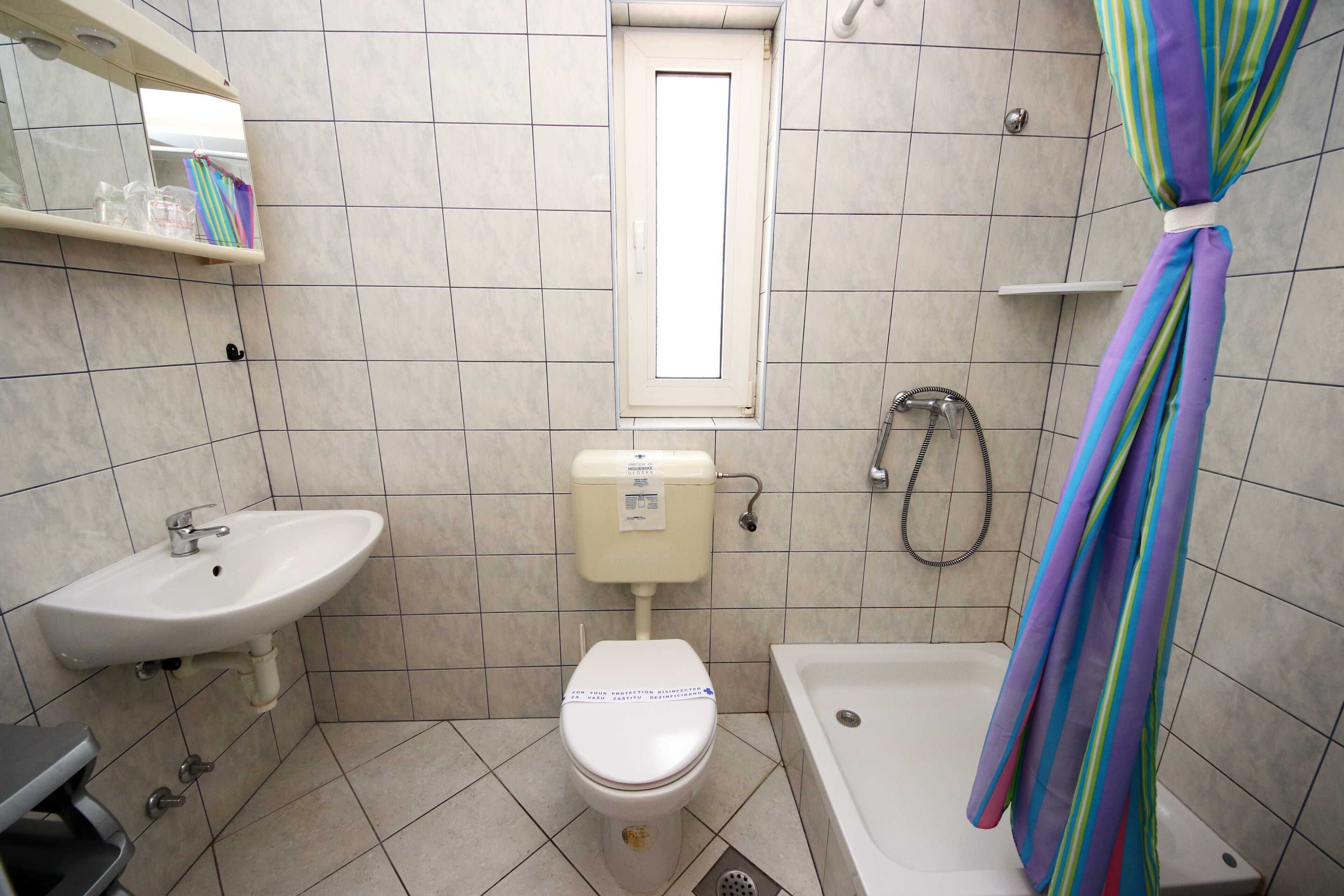 Et badeværelse med toilet, vask og badekar.