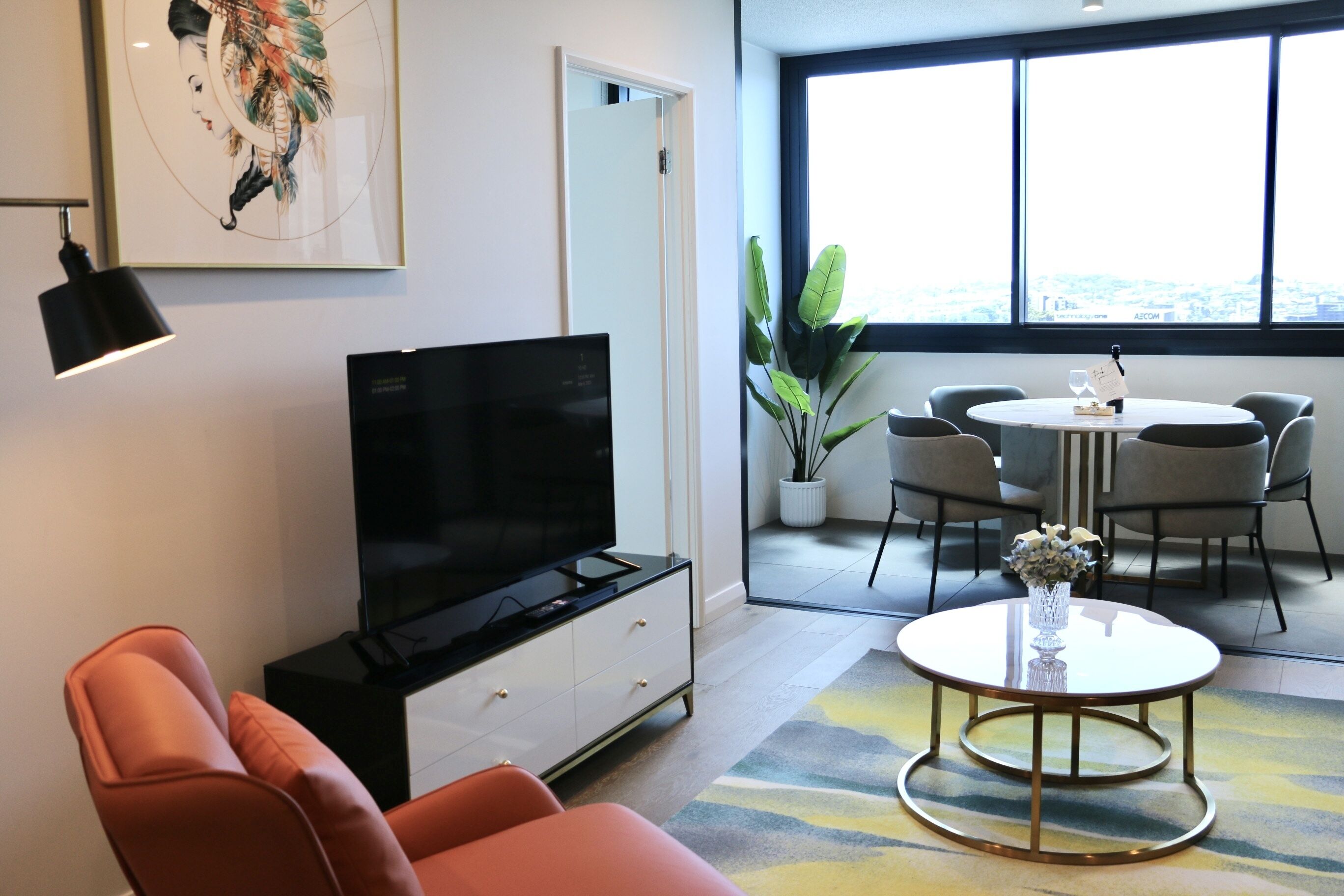 Una sala de estar moderna con televisor de pantalla plana, sofá naranja y una zona de comedor con mesa y sillas.