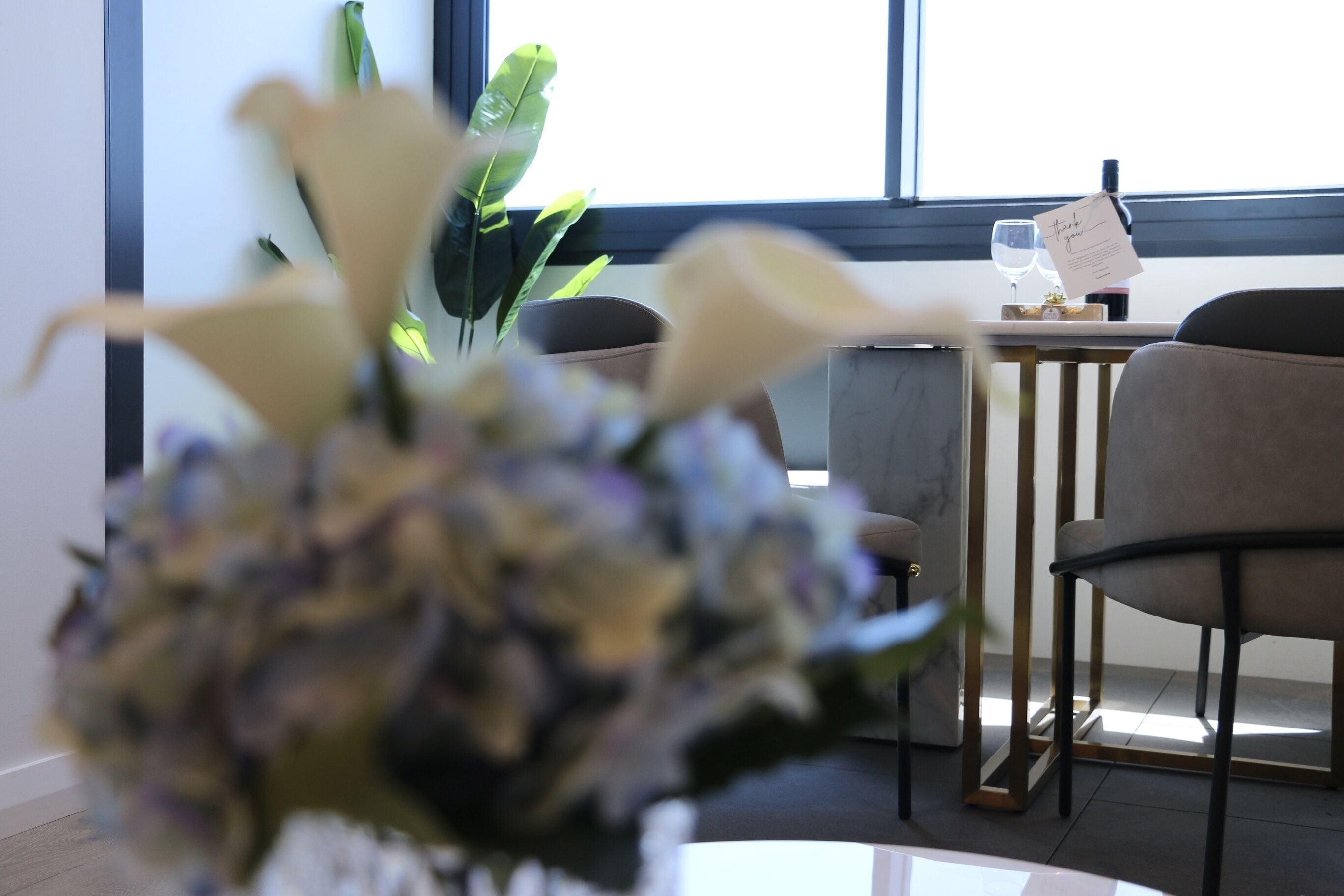 A room with a table, chairs, a potted plant, and a window with a view.