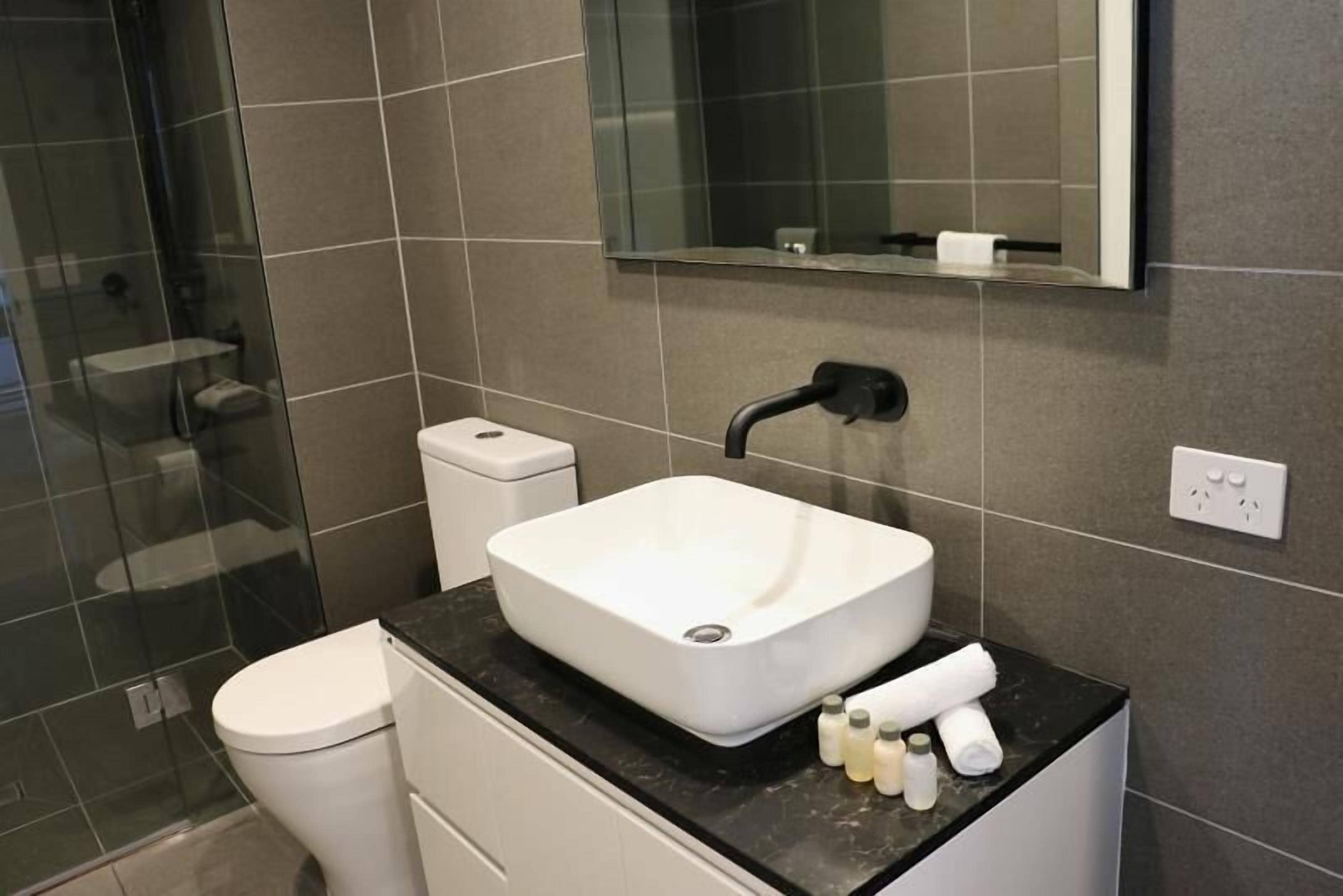 A modern bathroom with a white sink, a toilet, and a glass shower enclosure.