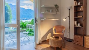 Une pièce avec vue sur les montagnes, une chaise en osier, une bibliothèque et un lampadaire.