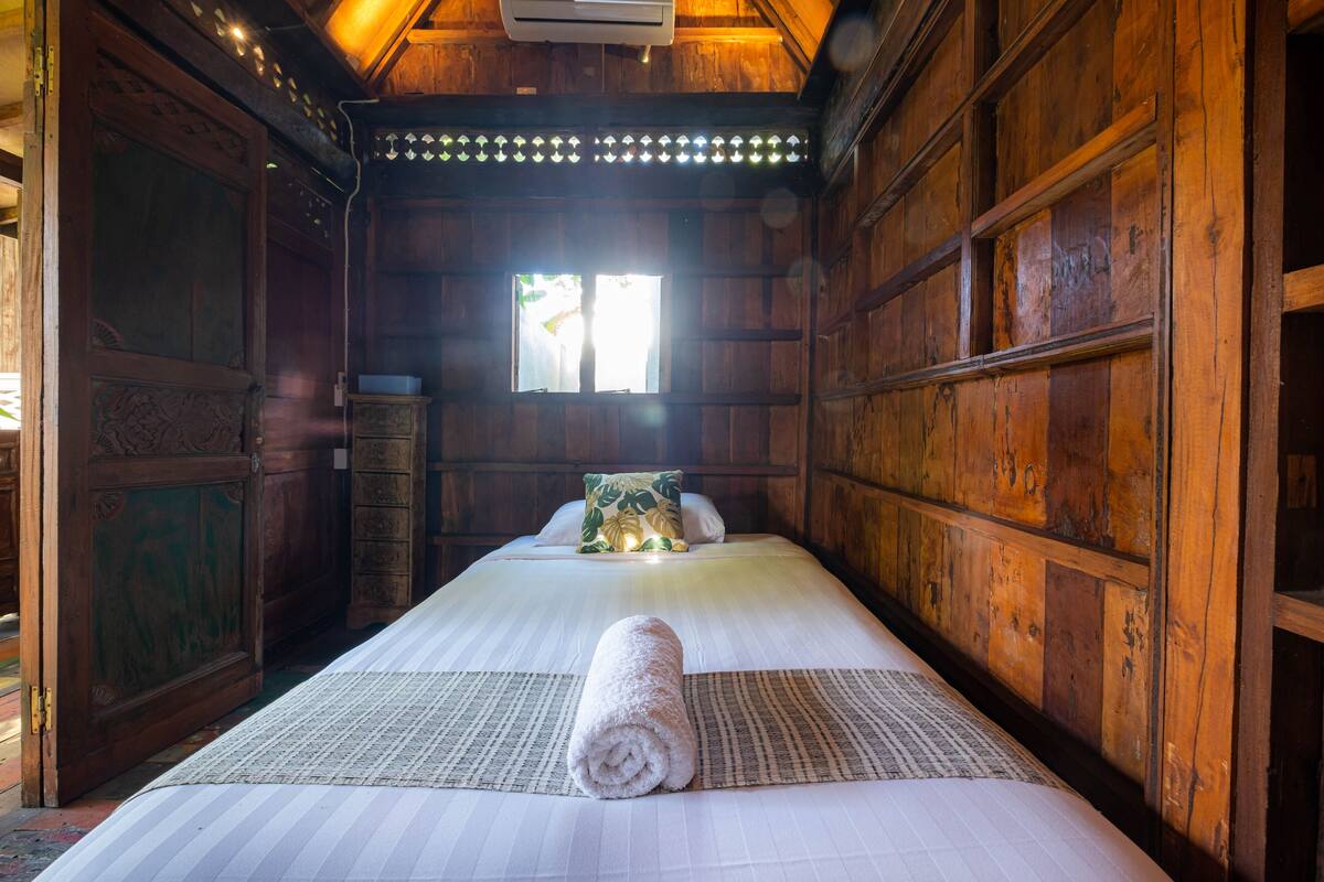 A wooden room with a bed, a window, and a door.
