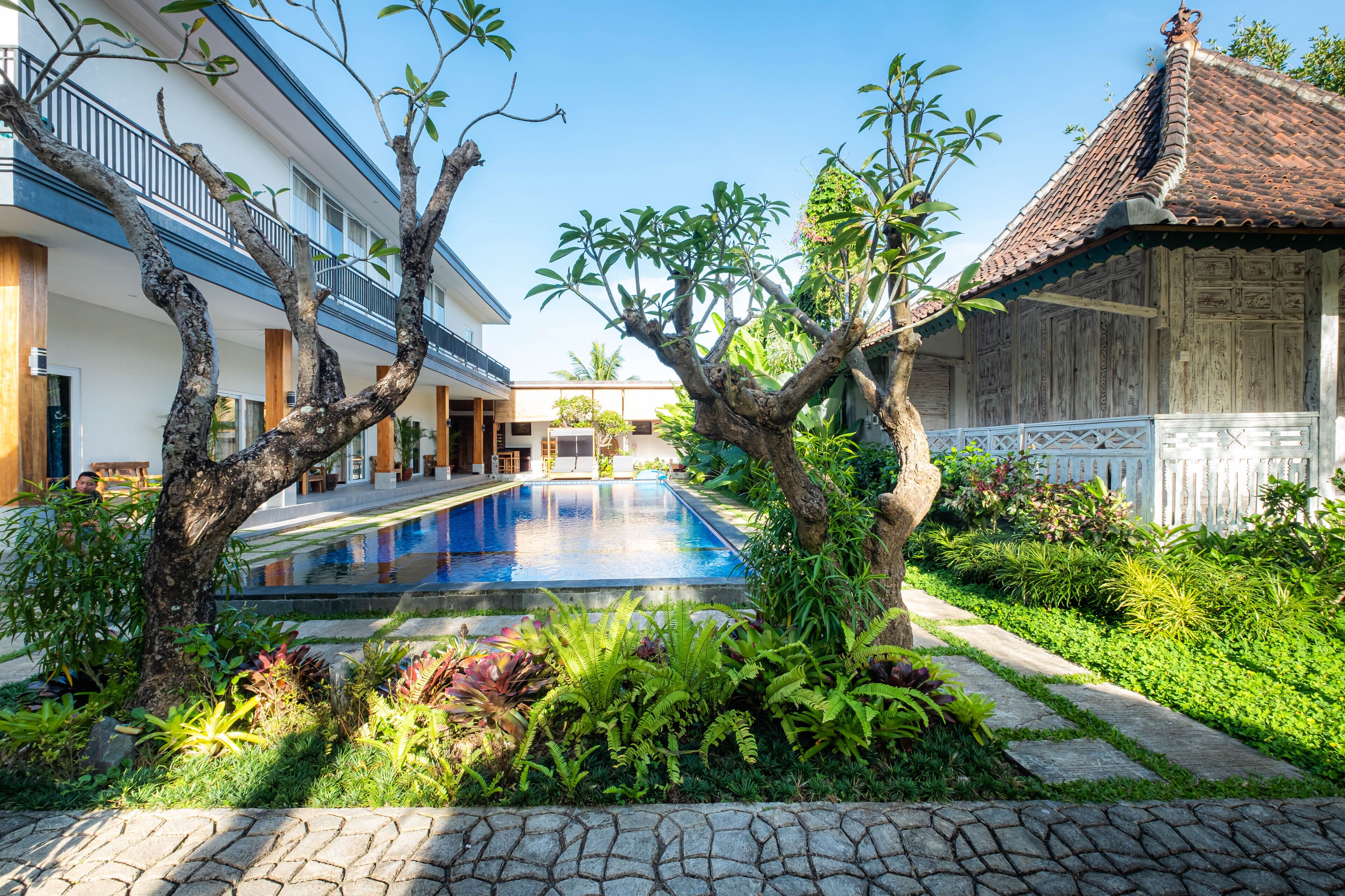 Una piscina rodeada de exuberante vegetación y arquitectura tradicional.