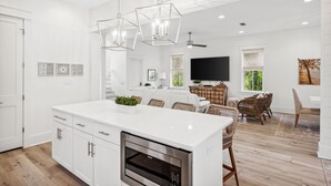 Une cuisine moderne avec des meubles blancs, un îlot central et un four encastré.
