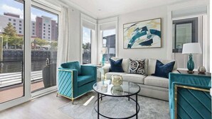 Una sala de estar moderna con un sofá, sillones, una mesa de centro de vidrio y un amplio ventanal con vista al río.