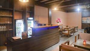 A bar area with a wooden counter, seating, and a refrigerator stocked with beverages.
