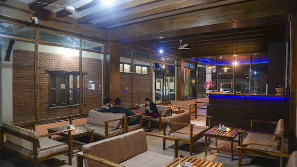 A cozy indoor seating area with wooden furniture and large windows.