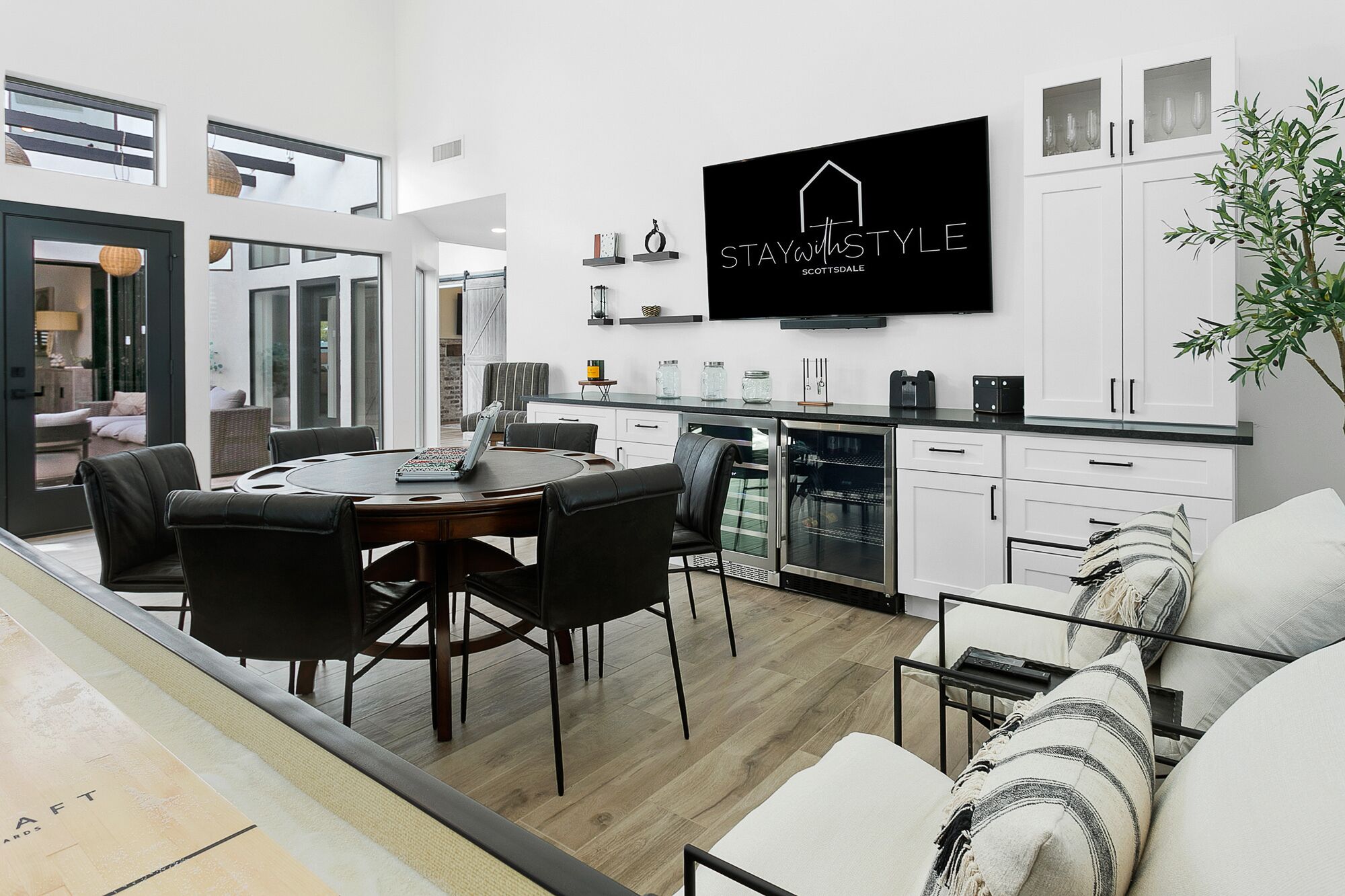 Une cuisine moderne avec des meubles blancs, un four encastré et un téléviseur à écran plat affichant le message « STAYWITHSTYLE ».