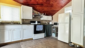 A compact kitchen with white cabinets, a black oven, and a white refrigerator.
