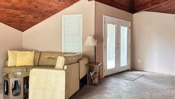A cozy living room with a beige sofa, a glass coffee table, a lamp, and a wooden cabinet.