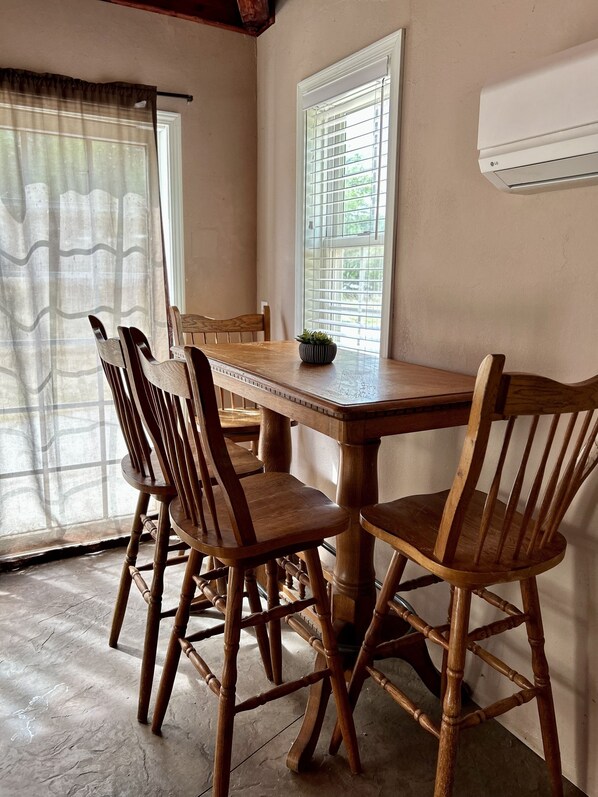 Un comedor con una mesa y sillas de madera, una planta en maceta y una ventana con persianas.